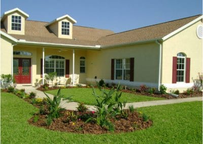 Show thumbnail preview Single-story yellow house with a brown roof, well-manicured lawn, and expertly designed landscaping featuring vibrant flower beds in the front yard.