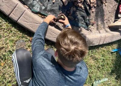 Person in long sleeve shirt and athletic pants working on garden/lawn edging outdoors, setting up landscape lighting.